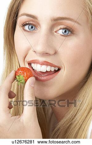 Stock Image - Portrait Of Young Woman Eating Strawberry. Fotosearch