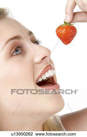 Stock Image - Portrait Of Young Woman Eating Strawberry. Fotosearch