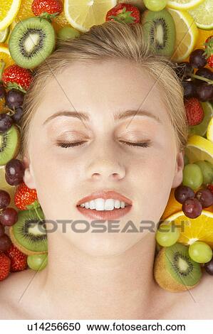 Stock Image - Portrait Of Young Woman Surrounded By Fruit. Fotosearch