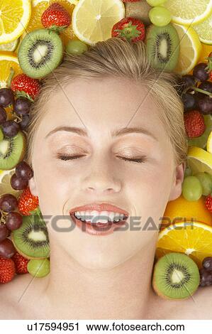 Stock Image - Portrait Of Young Woman Surrounded By Fruit. Fotosearch