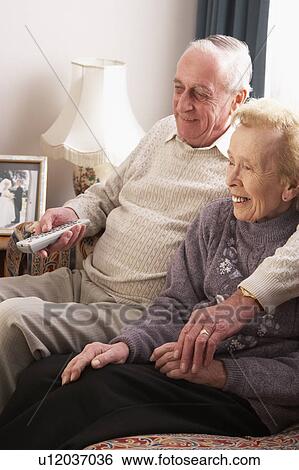 Stock Photograph - Senior Couple Watching TV At Home. Fotosearch