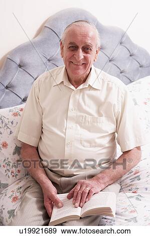 Stock Photo - Senior Man Reading Book On Bed. Fotosearch