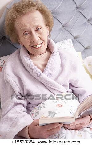 Picture - Senior Woman Relaxing In Bed With Book. Fotosearch