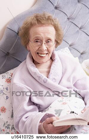 Stock Photography - Senior Woman Relaxing In Bed With Book. Fotosearch
