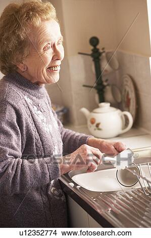 Picture - Senior Woman Washing Up At Sink. Fotosearch