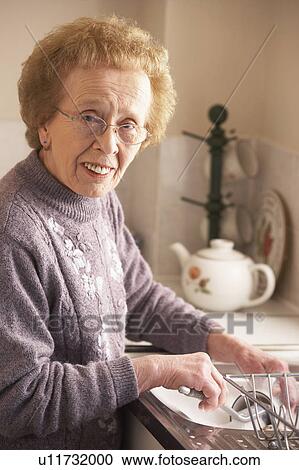 Stock Image - Senior Woman Washing Up At Sink. Fotosearch