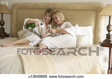 Stock Photo - Two Women Enjoying Champagne In Bedroom. Fotosearch