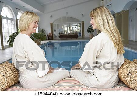Stock Image - Two Women Relaxing By Swimming Pool. Fotosearch