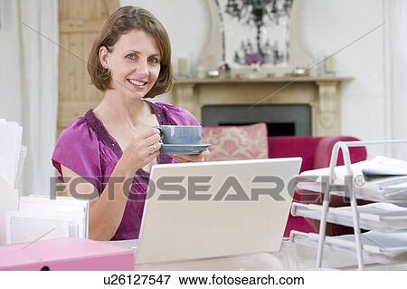 Woman drinking coffee at her desk View Large Photo Image Stock Photo - Woman drinking coffee at her desk. Fotosearch