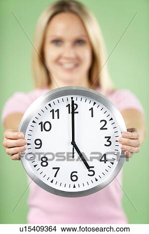 Picture - Woman Holding Clock Showing 5 O'Clock. Fotosearch