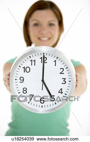 Stock Photo - Woman Holding Clock Showing 5 O'Clock. Fotosearch