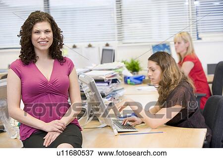 Woman sitting happily on a desk View Large Photo Image Stock Photo - Woman sitting happily on a desk. Fotosearch