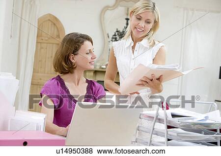 Stock Photo - Women looking at paperwork together. Fotosearch