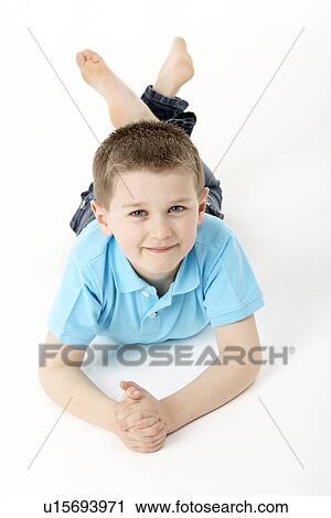 Stock Image - Young Boy Lying On Stomach In Studio. Fotosearch