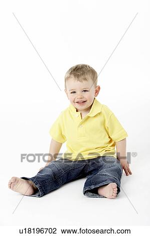 Stock Image - Young Boy Sitting In Studio. Fotosearch