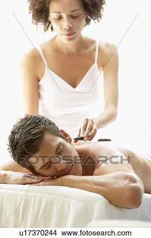 Picture - Young Man Enjoying Hot Stone Treatment. Fotosearch