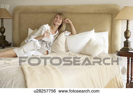 Stock Photograph - Young Woman Enjoying Champagne In Bedroom. Fotosearch