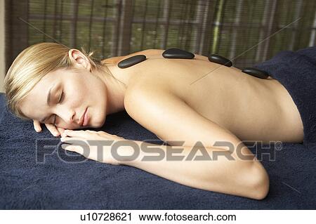 Stock Image - Young Woman Enjoying Hot Stone Treatment. Fotosearch