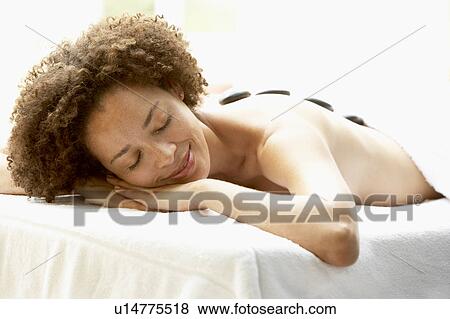 Stock Photo - Young Woman Enjoying Hot Stone Treatment. Fotosearch