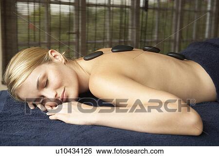 Stock Photograph - Young Woman Enjoying Hot Stone Treatment. Fotosearch