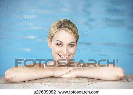 Stock Image - Young Woman Resting On Edge Of Swimming Pool. Fotosearch