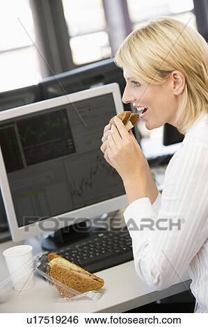 Stock Photograph - Businesswoman Enjoying Sandwich During Lunchbreak. Fotosearch