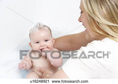 Stock Image - Mother Bathing Baby At Home. Fotosearch