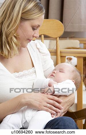 Stock Image - Mother Holding Baby In Nursery. Fotosearch