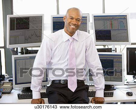 Stock Image - Portrait Of Stock Trader In Front Of Computer Monitors. Fotosearch