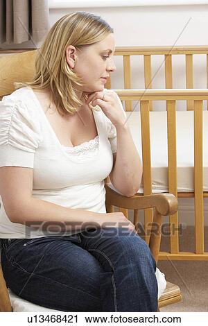 Stock Image - Sad Mother Sitting In Empty Nursery. Fotosearch