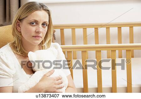 Stock Photo - Sad Mother Sitting In Empty Nursery. Fotosearch