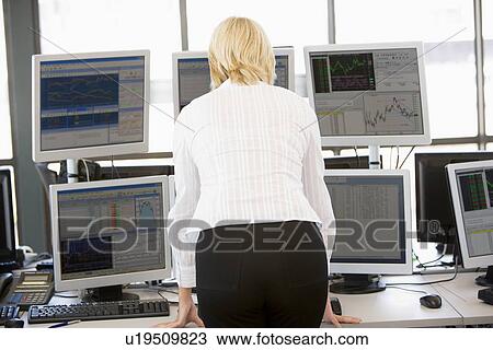 Stock Image - Stock Trader Looking At Multiple Monitors. Fotosearch