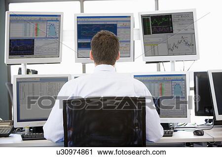 Stock Image - Stock Trader Looking At Multiple Monitors. Fotosearch