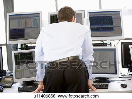 Stock Photo - Stock Trader Looking At Multiple Monitors. Fotosearch