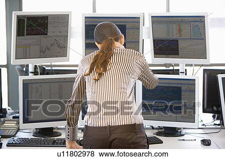 Stock Photo - Stock Trader Looking At Multiple Monitors. Fotosearch