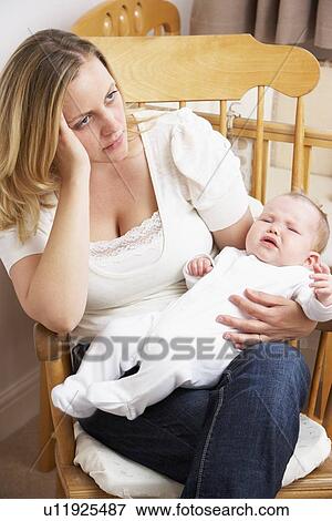 Stock Photo - Worried Mother Holding Baby In Nursery. Fotosearch