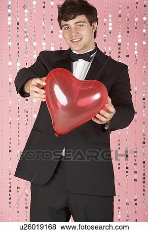 Stock Photo - Young Man Dressed In Suit Holding Heart. Fotosearch