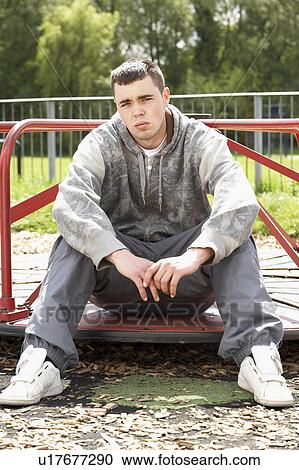 Stock Image - Young Man Sitting In Playground. Fotosearch
