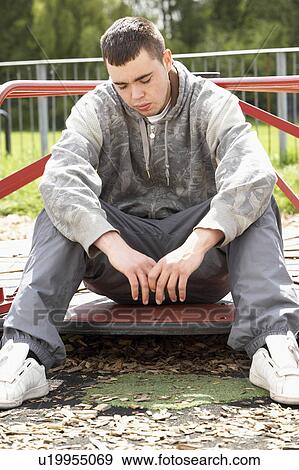 Stock Photo - Young Man Sitting In Playground. Fotosearch