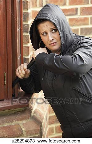 Stock Image - Young Woman Breaking Into House. Fotosearch