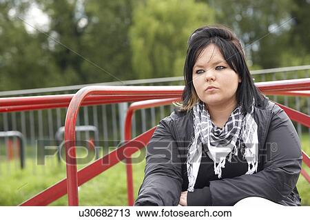 Stock Image - Young Woman Sitting In Playground. Fotosearch