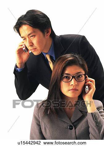 Stock Image - Businessman and businesswoman using mobile phone, Front View. Fotosearch