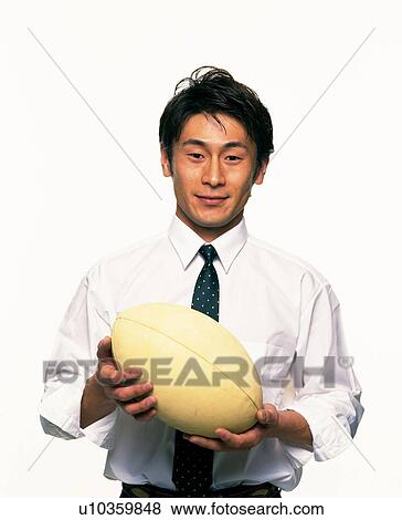 Stock Photo - Businessman holding a rugby ball, Front View. Fotosearch