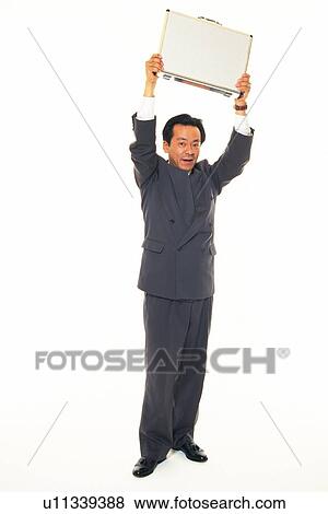 Businessman holding business case up in the air, Front View View Large Photo Image Stock Photo - Businessman holding business case up in the air, Front View. Fotosearch