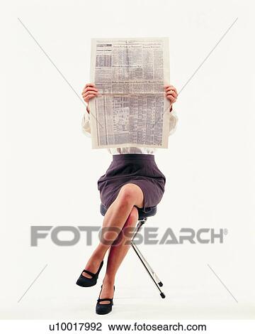 Stock Image - Businesswoman reading news paper with crossed legs, Front View. Fotosearch
