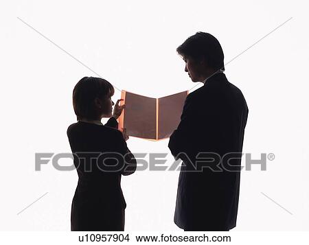 Picture - Bsinessman and businesswoman looking at documents together, Rear View, Silhouette . Fotosearch