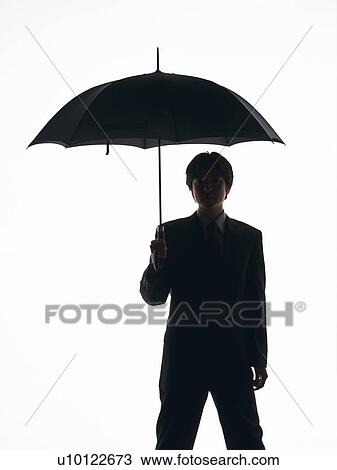 Stock Image - Bsinessman standing with umbrella, Front View, Silhouette . Fotosearch