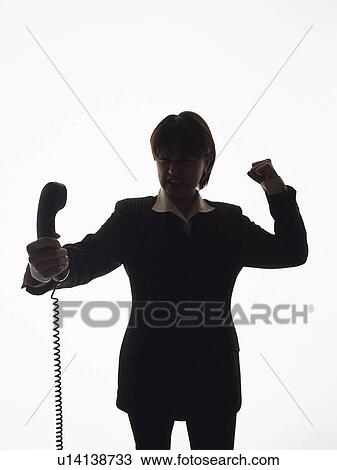 Stock Image - Bsinesswoman holding and yelling at handset, Front View, Silhouette . Fotosearch