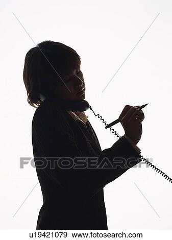 Stock Photo - Bsinesswoman talking on the phone with a pen in hand, Side View, Silhouette . Fotosearch