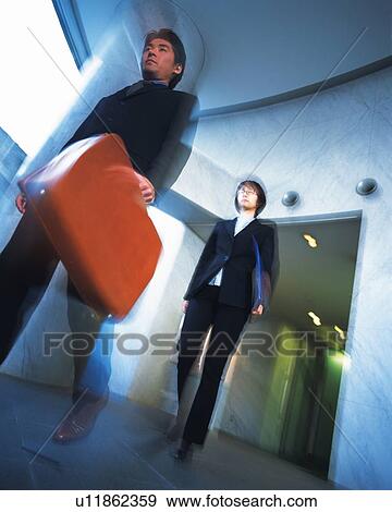Businessman and businesswoman Walking down the hallway, Portrait, Low Angle View, Blurred Motion View Large Photo Image Stock Photo - Businessman and businesswoman Walking down the hallway, Portrait, Low Angle View, Blurred Motion. Fotosearch